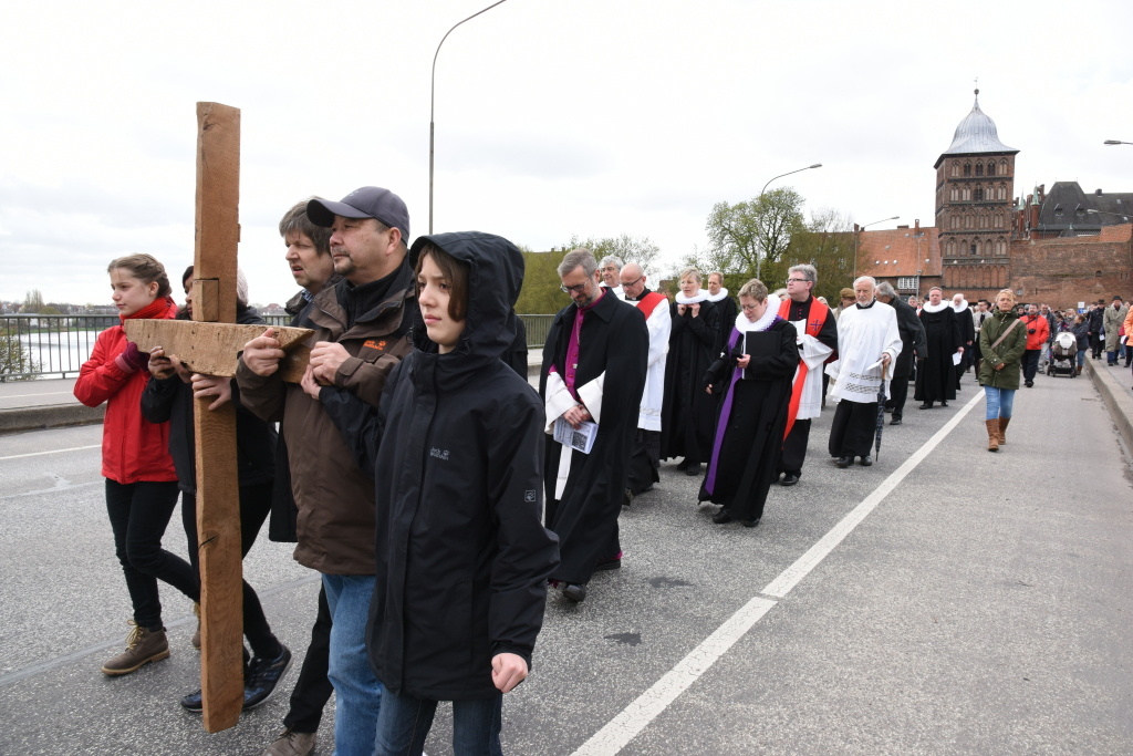 Menschen gehen in einer Prozession mit einem großen Holzkreuz beim Lübecker Kreuzweg am Karfreitag 2017. (Foto: KNA)