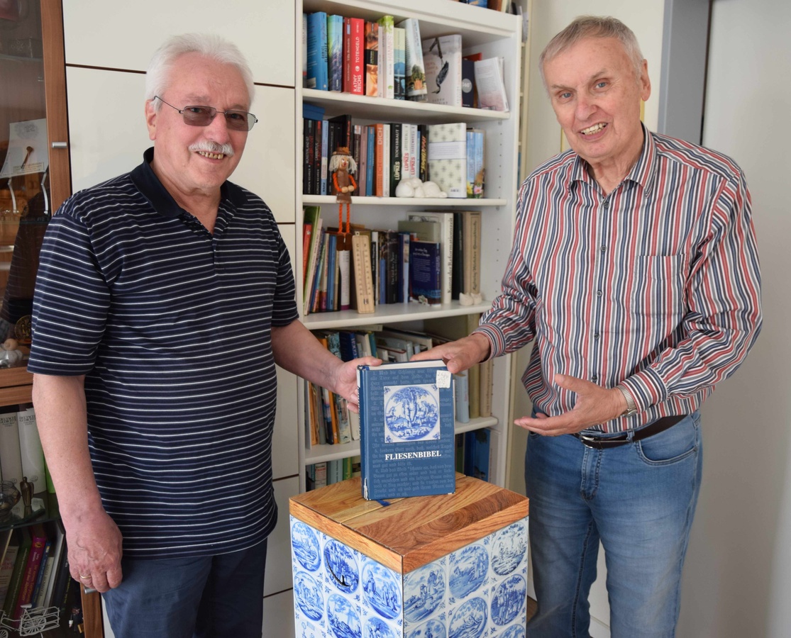 Gerd Endemann (links) und Kurt Perrey posieren mit der „Fliesenbibel“. Sie ist mit rund 600 Bibelfliesen-Darstellungen illustriert. (Foto: Kay Müller)