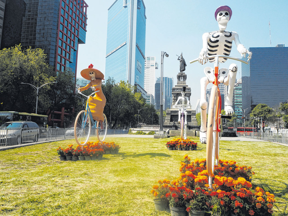 Hauptfigur des Tags der Toten ist ein grinsendes Skelett mit Kleid und breitem Hut (links). Hier radelt „La Catrina“ mit anderen Toten durch Mexiko-Stadt. (Foto: Boixaidós)