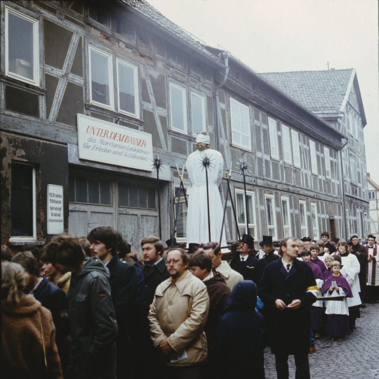 Eine katholische Palmsonntagsprozession 1983 in Heiligenstadt. Auf dem Schild über der Hofeinfahrt steht: „Unter dem Banner des Marxismus-Leninismus für Frieden und Sozialismus.“ (Repro: Vallendar)