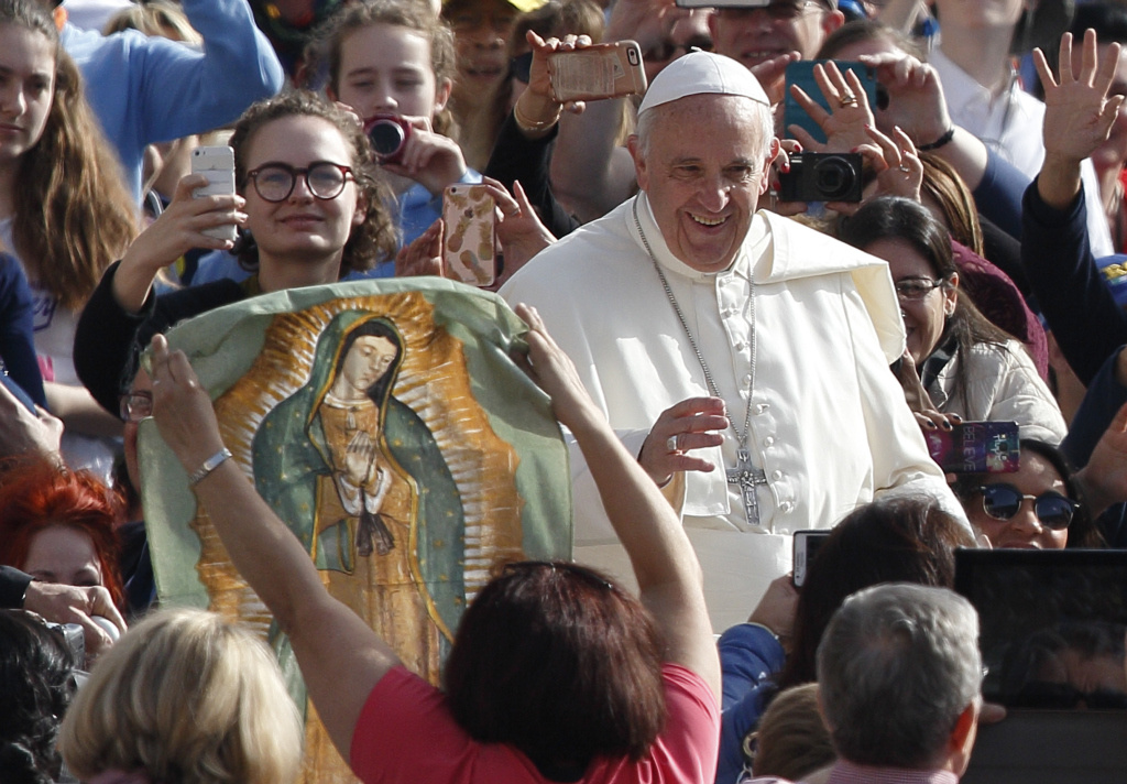 Papst Franziskus geht lächelnd an einem Banner von „Unserer lieben Frau von Guadalupe“ vorbei, während er bei der Generalaudienz die Menge grüßt. (Foto: KNA)