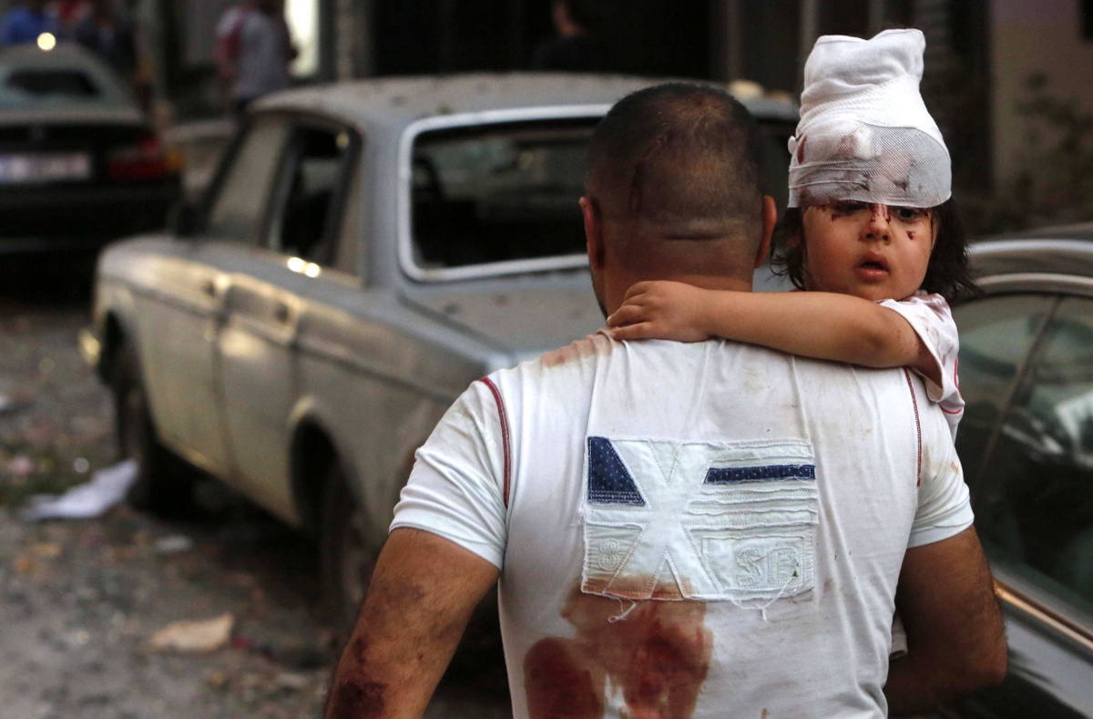 Ein Mann bringt nach der Explosion im Hafen von Beirut am 4. August 2020 ein verletztes Kind in Sicherheit. (Foto: imago images/Zuma Wire) 