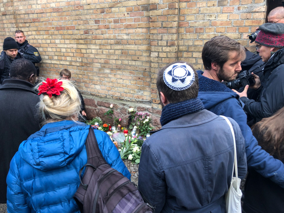 Menschen gedenken mit Blumensträußen und Kerzen an der Mauer der Synagoge in Halle (Saale) am 10. Oktober 2019 nach dem Anschlag am Tag zuvor. (Foto: KNA)