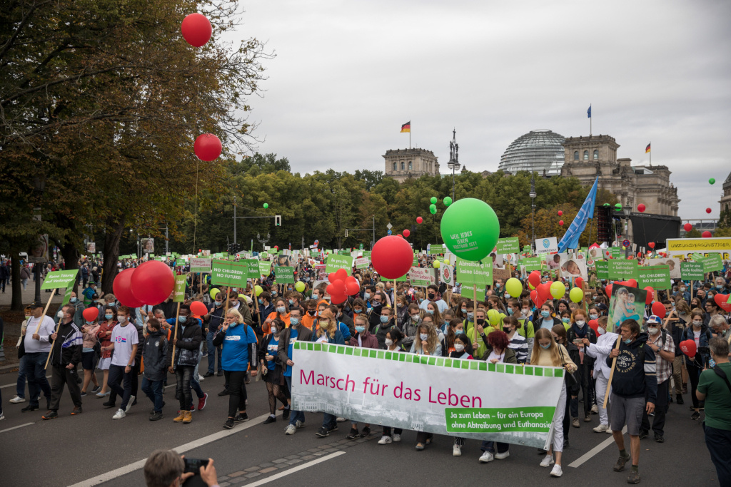 Demonstranten stehen hinter einem großen Banner mit der Aufschrift "Marsch für das Leben" und halten rote und grüne Luftballons und Schilder mit verschiedenen Aufschriften beim "Marsch für das Leben" gegen Abtreibung und aktive Sterbehilfe am 18. September 2021 in Berlin. (Foto: KNA)