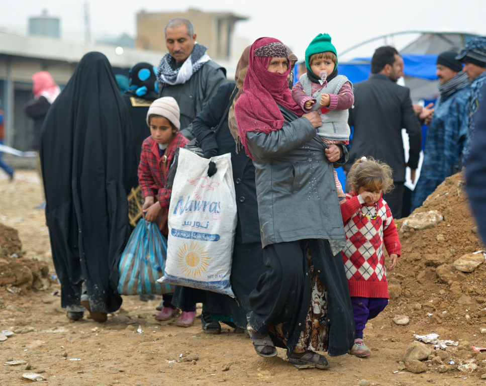 Eine Flüchtlingsfamilie mit mehreren Kindern verlässt ein Zentrum zur Registrierung Geflohener in der Nähe von Mossul. (Foto: KNA)