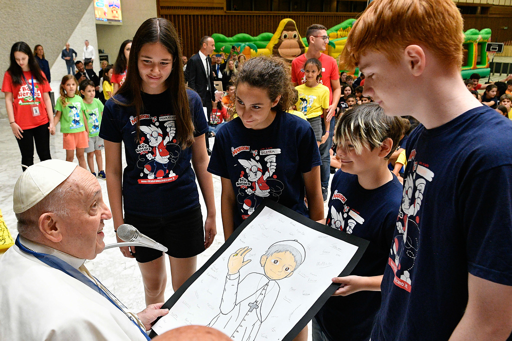Papst Franziskus trifft Kinder, die am Sommercamp "Estate Ragazzi in Vaticano" (dt. Sommerjugend im Vatikan) teilnehmen, am 18. Juli 2023 im Vatikan. Sie überreichen ihm ein gezeichnetes Porträt von ihm. (Foto: KNA)