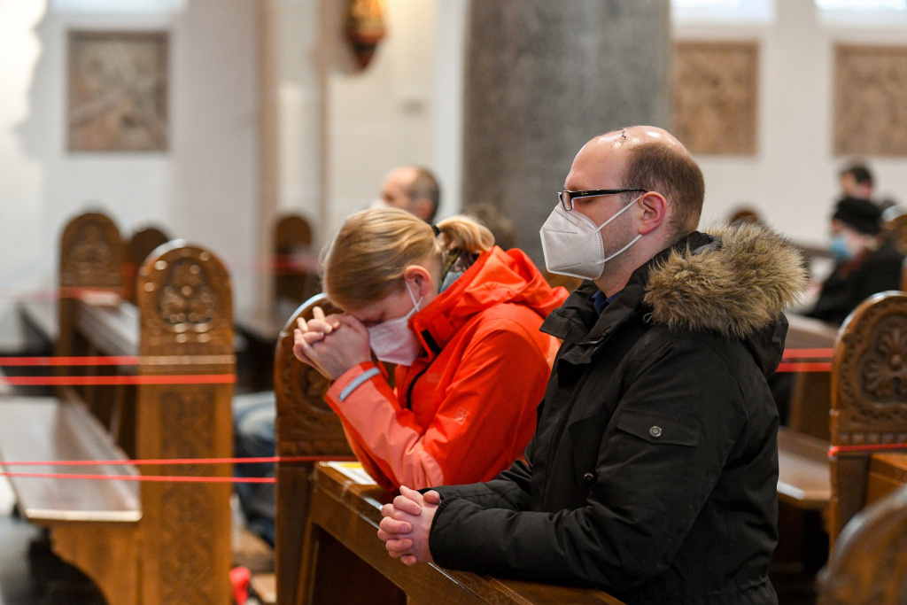 Ein Mann und eine Frau tragen FFP2-Masken und knien zum Gebet in einem Gottesdienst am 17. Februar 2021 in Bonn. (Foto: KNA)