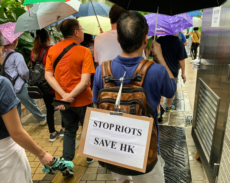 Demonstration der Demokratiebewegung im Regierungsviertel Admiralty in Hongkong am 17. August 2019. Ein Demonstrant trägt ein Schild mit der Aufschrift "Stop Riots - Save HK" (dt. "Stoppt die Randalierer. Rettet Hongkong"). (Foto: KNA)