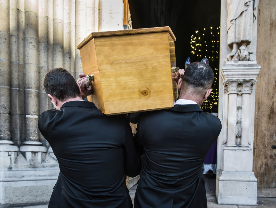 Männer in schwarzen Anzügen tragen einen Sarg aus Holz zum Requiem in eine Kirche. (Foto: KNA)