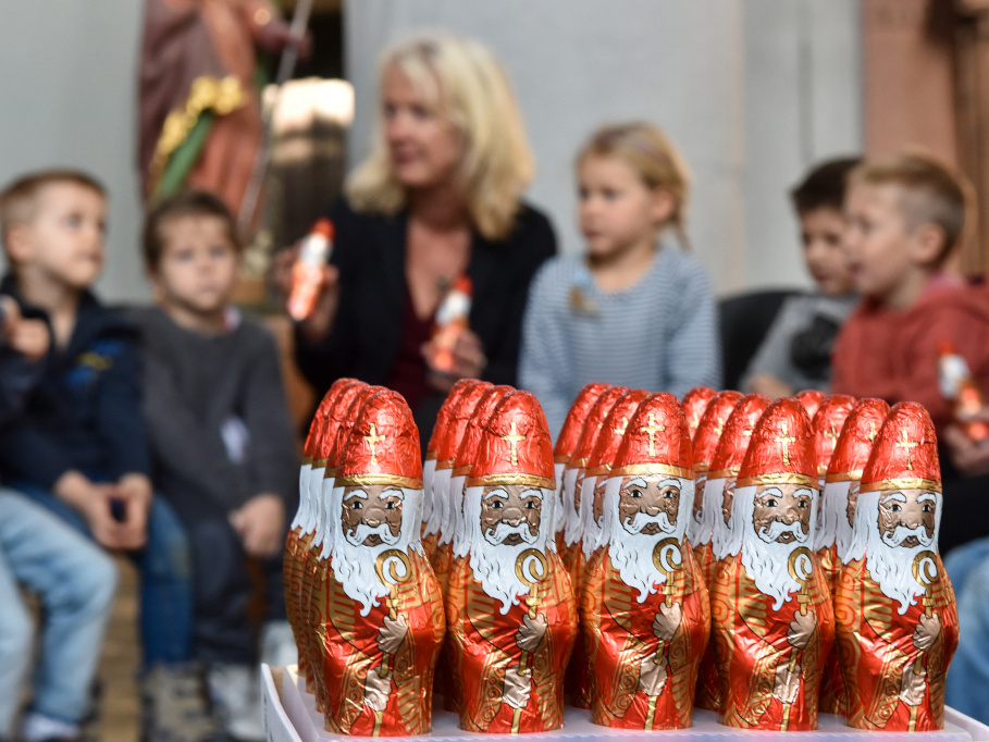 Fair gehandelte Schoko-Nikoläuse stehen in der Sankt-Nikolaus-Kirche in Aachen. Dahinter sitzen Kindergartenkinder und Mitarbeiterinnen von den Organisationen GEPA und Misereor, die die Nikoläuse verteilen werden. (Foto: KNA)