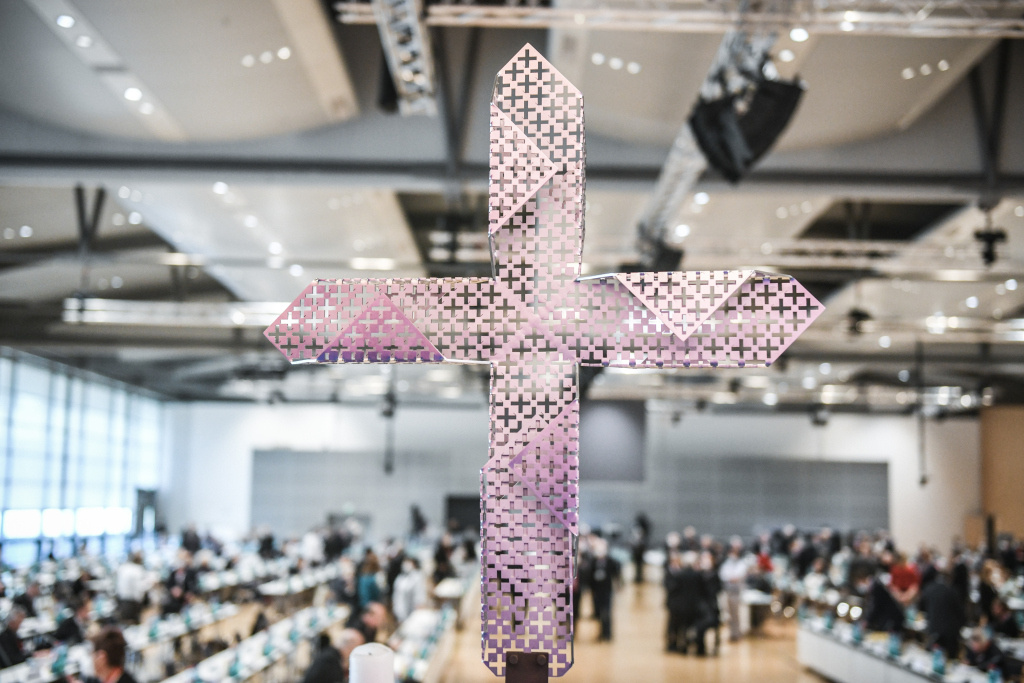 Blick in den Sitzungssaal im Congress Center der Frankfurter Messe während der zweiten Synodalversammlung am 1. Oktober 2021 in Frankfurt. Im Vordergrund steht ein gelochtes Metallkreuz. (Foto: KNA)