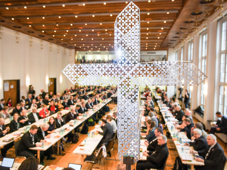 Blick durch das synodale Metallkreuz auf die Teilnehmer an langen Tischen bei den Beratungen der Synodalversammlung am 31. Januar 2020 im Dominikanerkloster in Frankfurt. (Foto: KNA)
