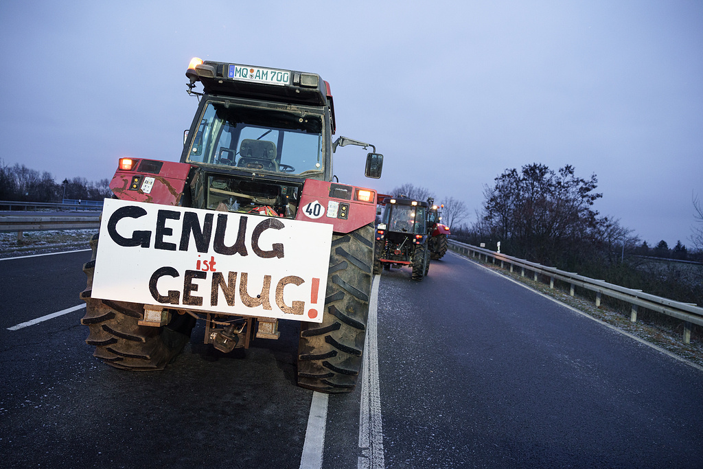 Ein Traktor steht im Morgengrauen am 8. Januar 2024 auf der Autobahn in Leipzig. An der Rückseite ist ein Schild angebracht mit der Aufschrift "Genug ist genug". (Foto: KNA)