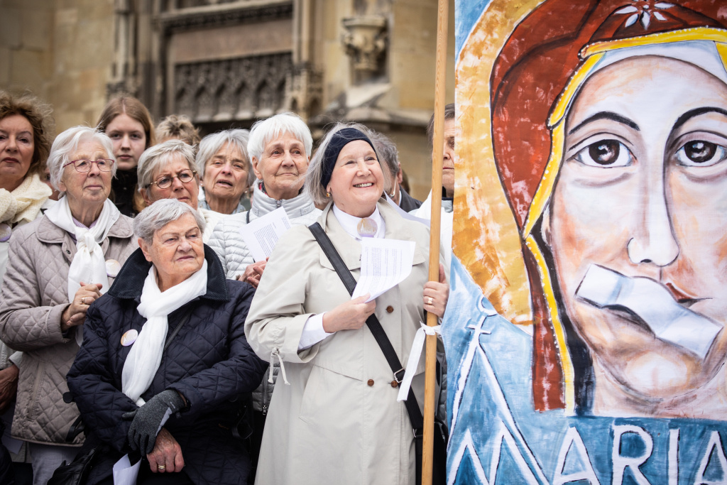 Am 12. Mai 2019 hielten Frauen bei einer Mahnwache vor dem Dom zu Münster ein Plakat, das Maria mit zugeklebtem Mund zeigt. (Foto: KNA)