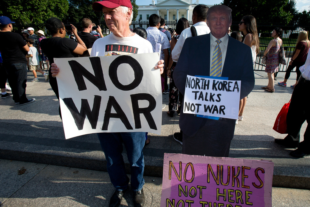 Menschen demonstrieren gegen einen Atomkrieg und Nuklearwaffen vor dem Weißen Haus am 9. August 2017 in Washington. Ein Demonstrant hält ein Plakat mit der Aufschrift "NO WAR" (dt. "Kein Krieg"). Neben ihm steht ein Pappaufsteller von US-Präsident Donald Trump mit einem Plakat "NORTH KOREA TALKS NOT WAR" (dt. "Gespräche mit Nordkorea, kein Krieg"). (Foto: KNA)