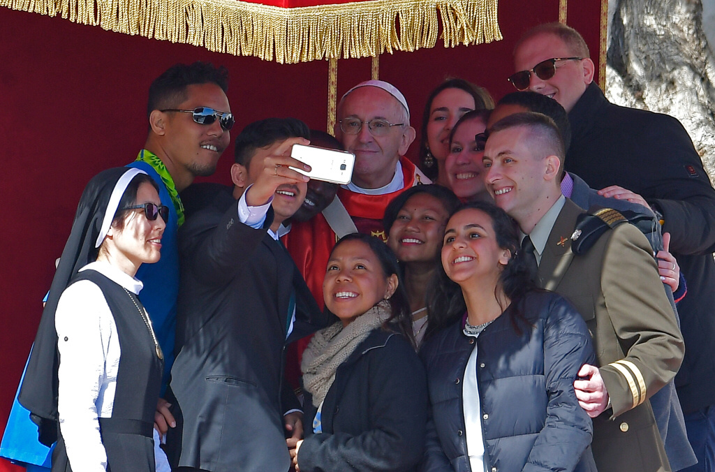 Junge Menschen machen ein Selfie mit Papst Franziskus an Palmsonntag auf dem Petersplatz. (Foto: KNA)